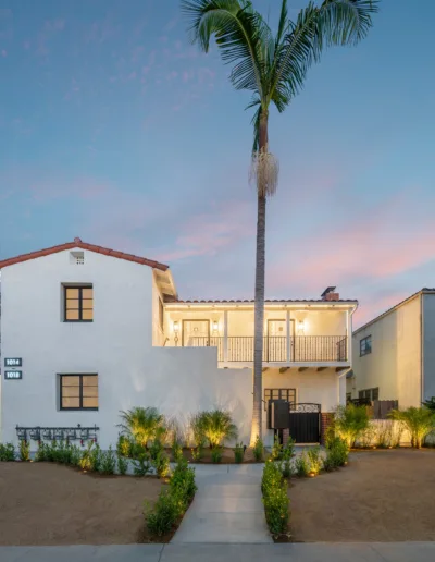 A home with a palm tree in front of it at dusk.