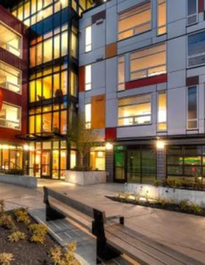 A modern apartment building at night with colorful lights.