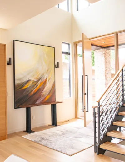 An entryway with a wooden staircase and a painting.