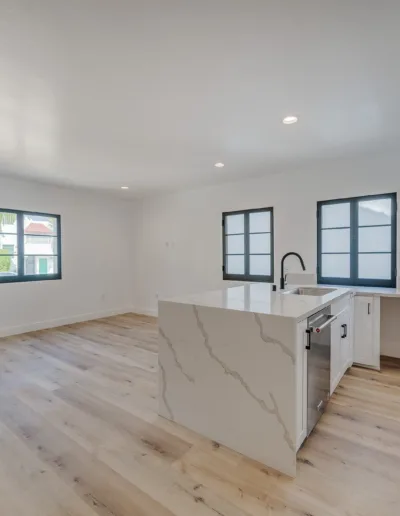 An empty kitchen with wood floors and white walls.