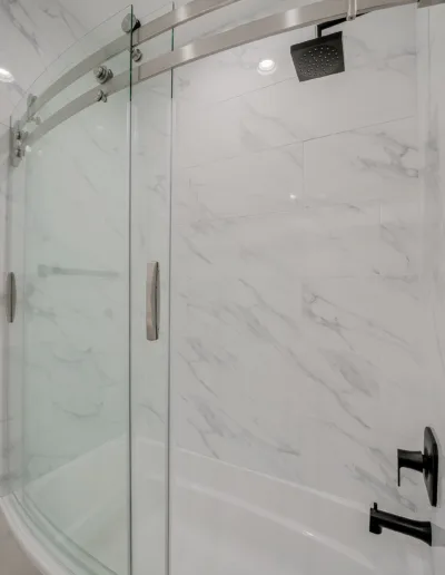 A white bathroom with a glass shower door.