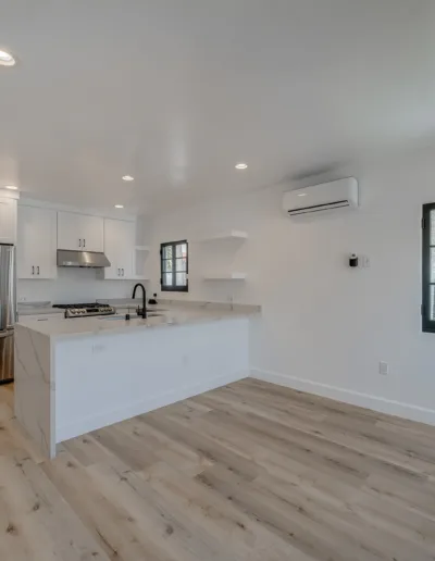 An empty kitchen with wood floors and white walls.