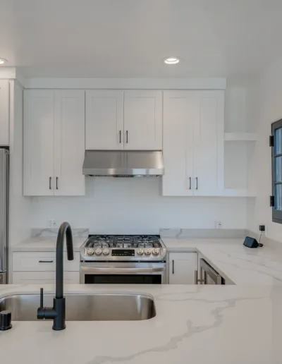 A white kitchen with stainless steel appliances and marble counter tops.