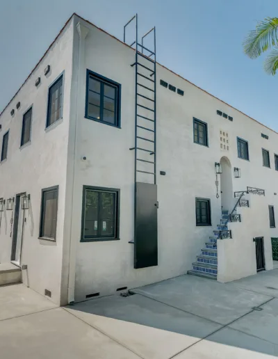 A white building with stairs and palm trees.