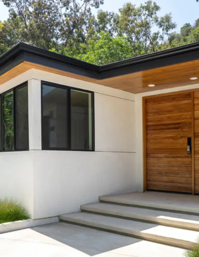 A white house with a wood door and stairs.