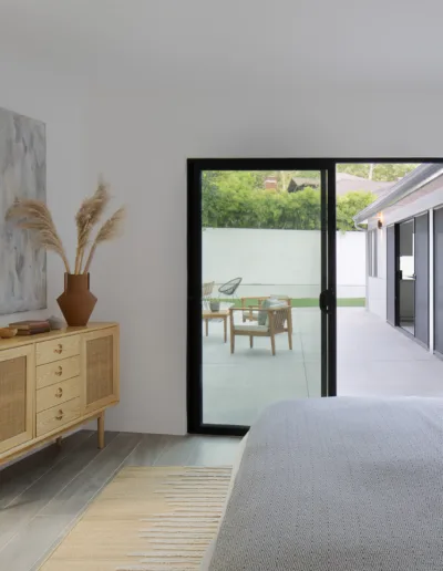 A bedroom with sliding glass doors and a white bed.