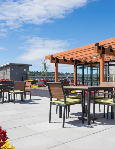 A rooftop patio with tables, chairs and flowers.