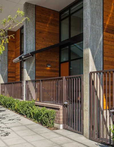 A sidewalk next to a building with a fence.