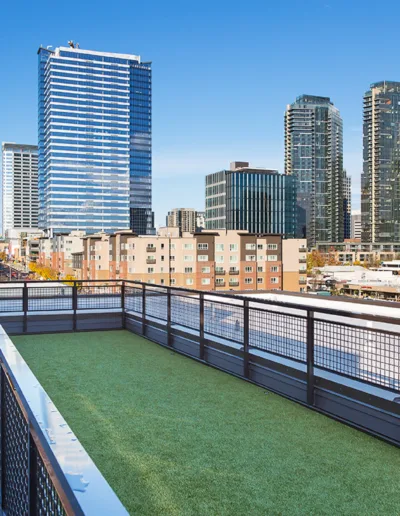 A balcony with a green grass and a view of a city.