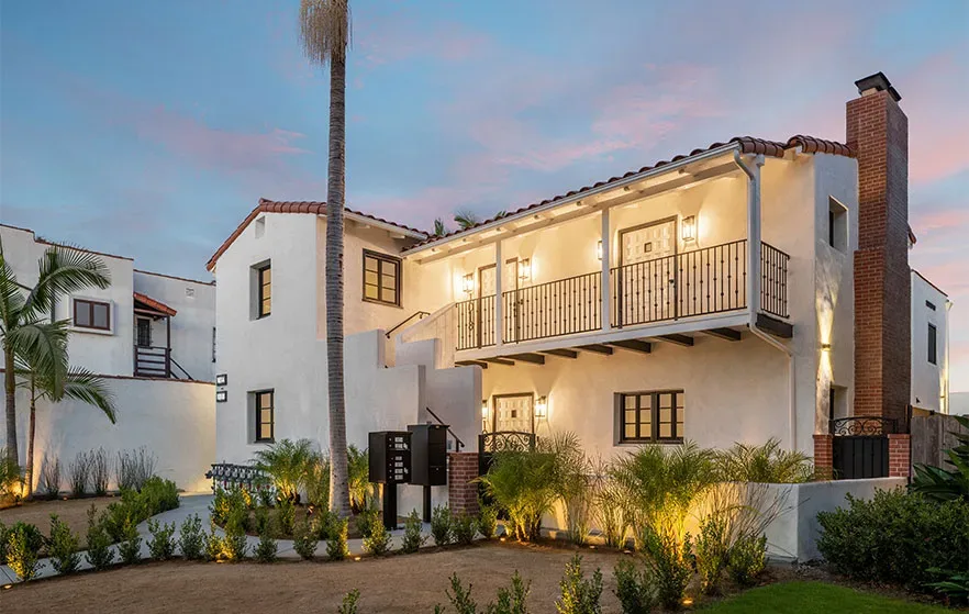 A home with a balcony and palm trees at dusk.